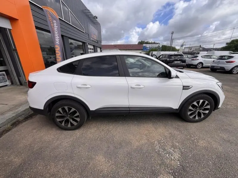 Profil côté gauche du Renault Arkana blanc perle 2023 avec jantes alu noires et vitres teintées.