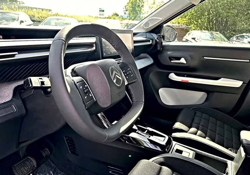 Vue intérieure côté conducteur du Citroën C3 Aircross 2026, volant multifonction et sellerie noire avec inserts gris.