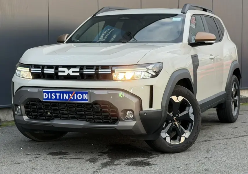 SUV Dacia Duster beige Sandstone en 3/4 avant droit, avec jantes alliage noires et phares allumés.