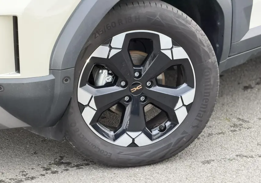 Gros plan sur la roue avant droite du Dacia Duster Beige Sandstone avec jante alliage noire et argentée.