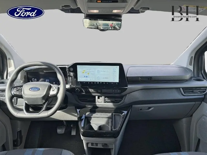 Vue intérieure avant du Ford Transit Custom gris, tableau de bord moderne avec écran tactile central et volant multifonctions.