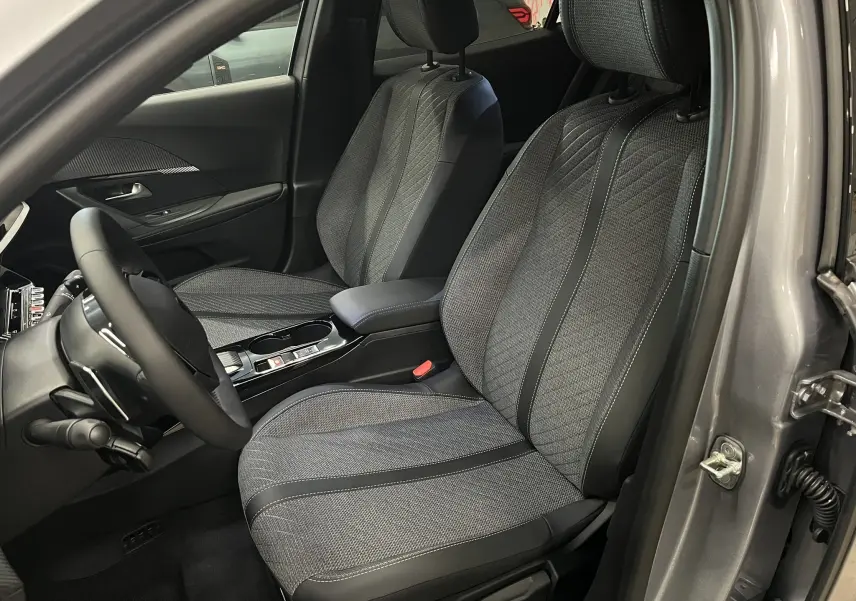 Vue intérieure côté conducteur du Peugeot 2008 gris Artense, mettant en valeur les sièges tissu et cuir noir au design moderne.