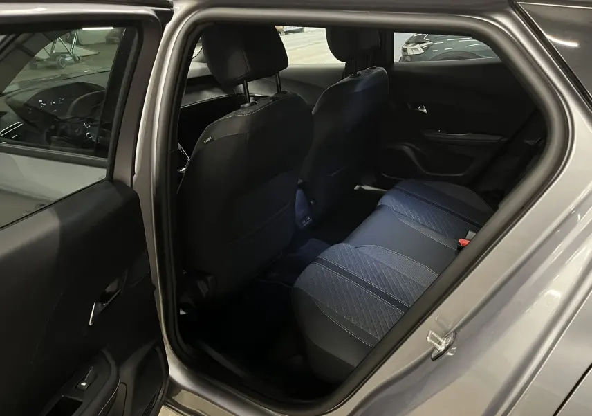 Vue intérieure côté arrière gauche du Peugeot 2008 gris Artense, montrant les sièges arrière en tissu et cuir noir.