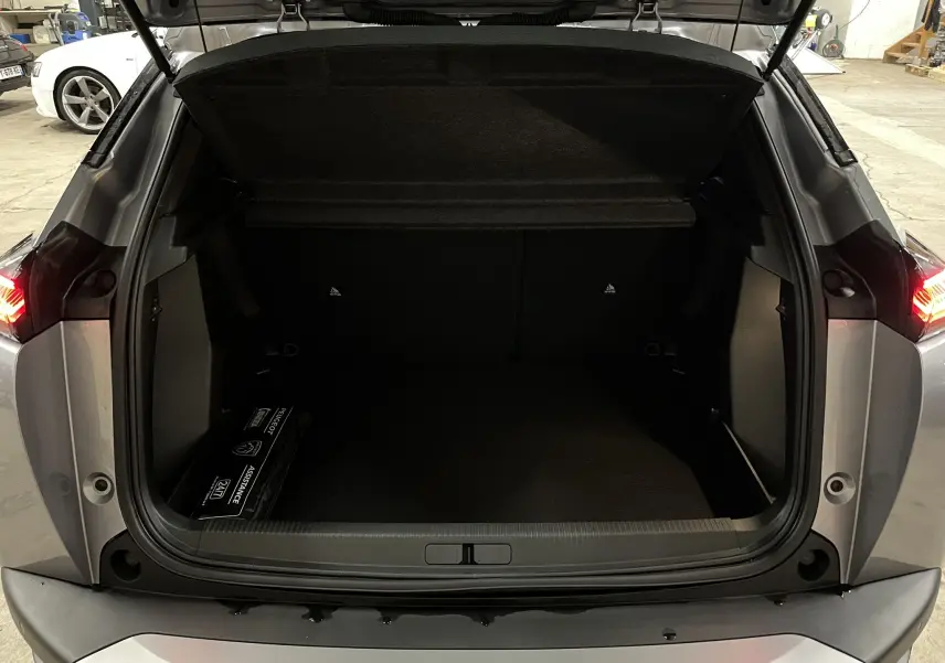 Coffre ouvert vu de l'arrière d'un Peugeot 2008 gris Artense Métal, avec espace de chargement vide et trousse d'assistance.