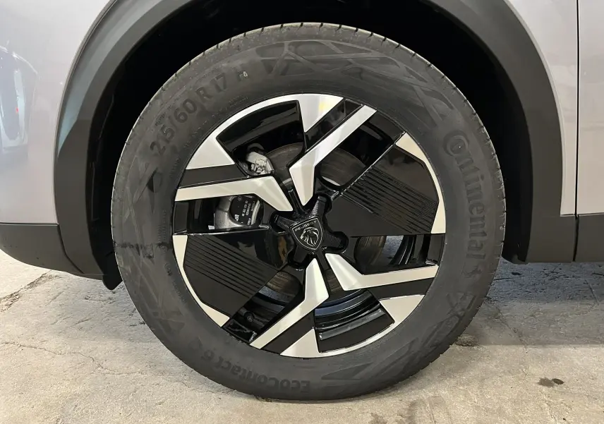 Gros plan sur la roue avant droite du Peugeot 2008 gris Artense, mettant en valeur la jante noire et argentée au design moderne.