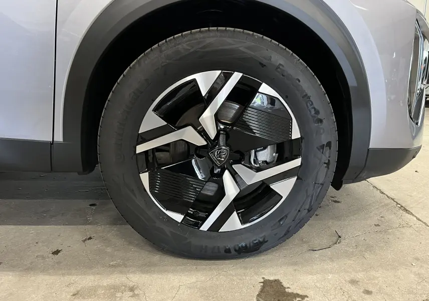 Gros plan sur la roue avant droite du Peugeot 2008 gris Artense Métal, mettant en valeur la jante bi-ton noire et argentée.