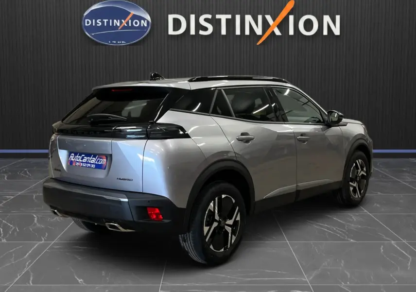 Peugeot 2008 gris Artense métal en 3/4 arrière droit, toit noir et jantes bi-ton visibles en intérieur showroom.