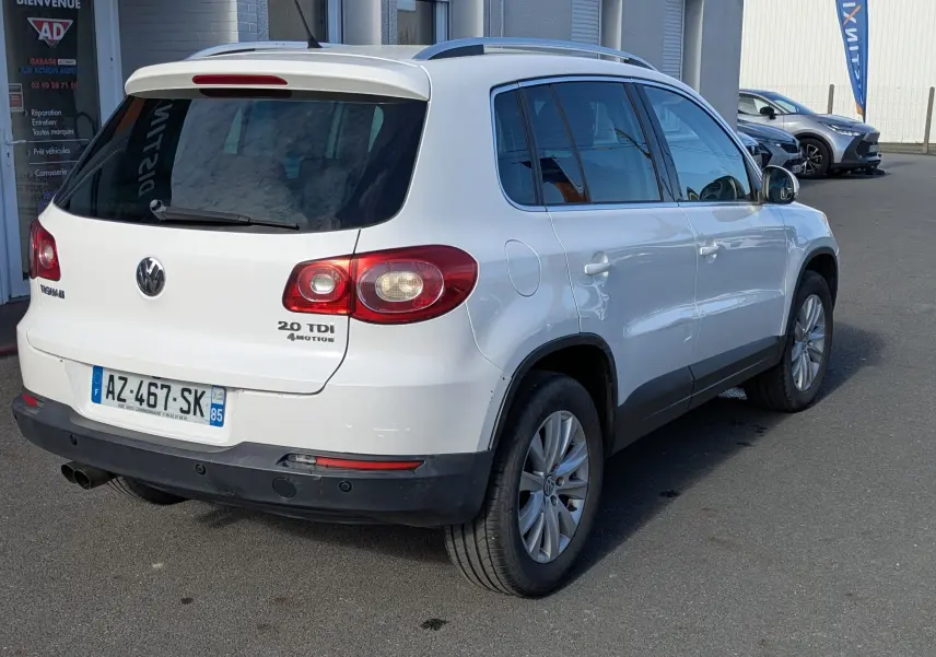 Vue 3/4 arrière droite d'un Volkswagen Tiguan blanc 2.0 TDI avec jantes alu et toit ouvrant électrique.