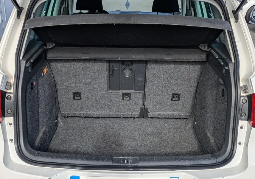 Coffre ouvert vue arrière d'un Volkswagen Tiguan blanc de 2010 avec intérieur de coffre gris et hayon relevé.