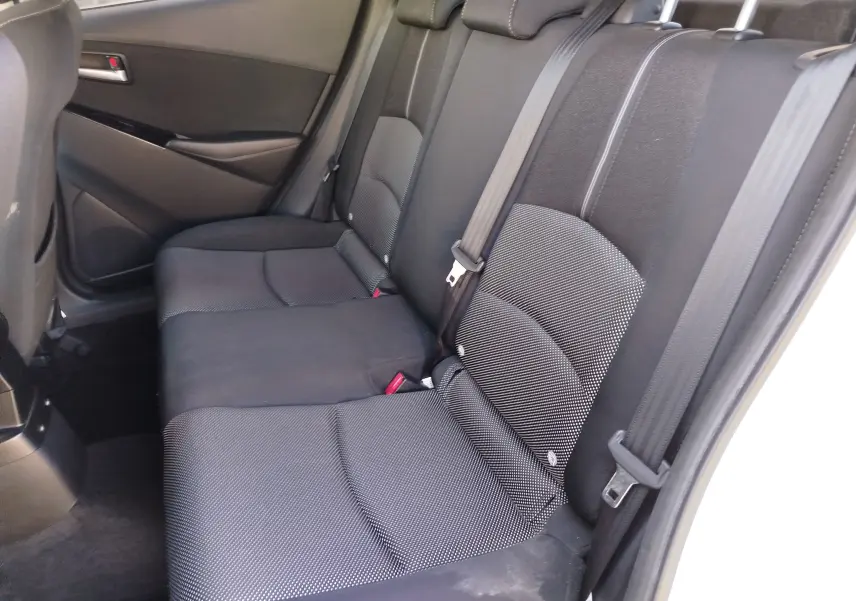 Vue intérieure des sièges arrière noirs en tissu de la Mazda2 2018, côté droit avec ceinture de sécurité visible.