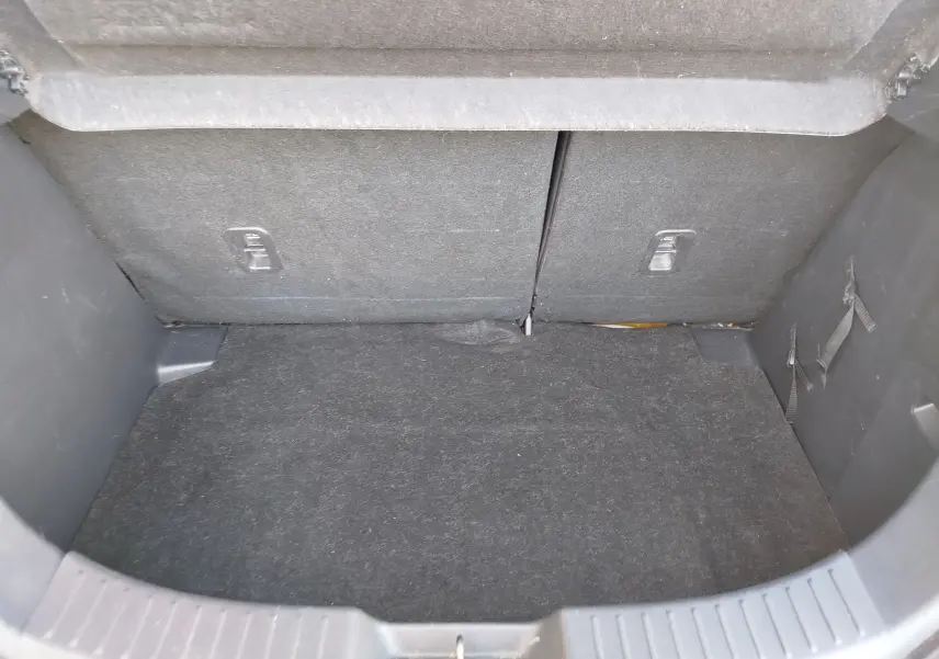 Coffre vide vu de l'arrière d'une Mazda2 2018 blanche, avec revêtement intérieur en tissu gris foncé.