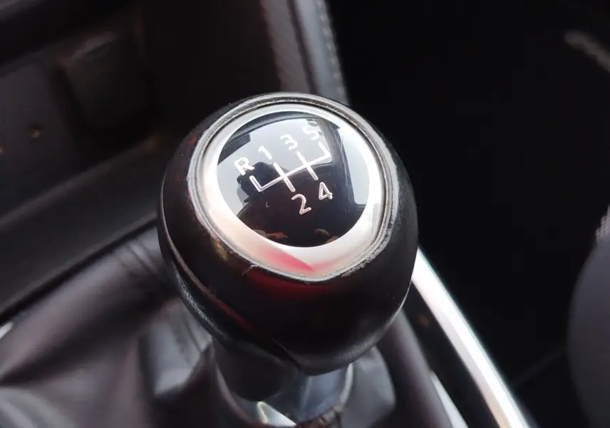 Gros plan sur le levier de vitesses manuel noir de la Mazda2 2018, montrant la grille des 5 rapports et la marche arrière.