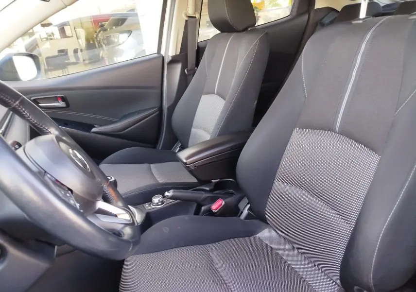 Vue intérieure côté conducteur de la Mazda2 2018 avec sièges tissu gris et volant cuir noir.