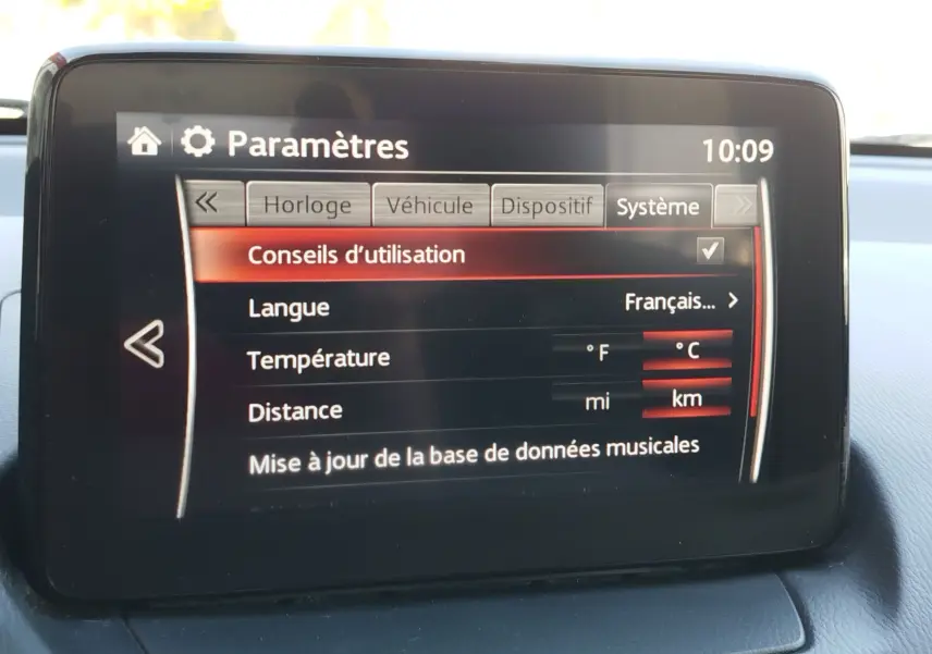 Écran central de la Mazda2 montrant le menu des paramètres système avec options de langue, température et distance.