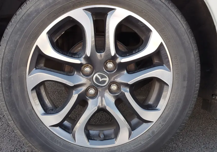 Gros plan sur la jante alliage bicolore de la Mazda2 Snowflake White Pearl Mica de 2018, avec logo Mazda central.