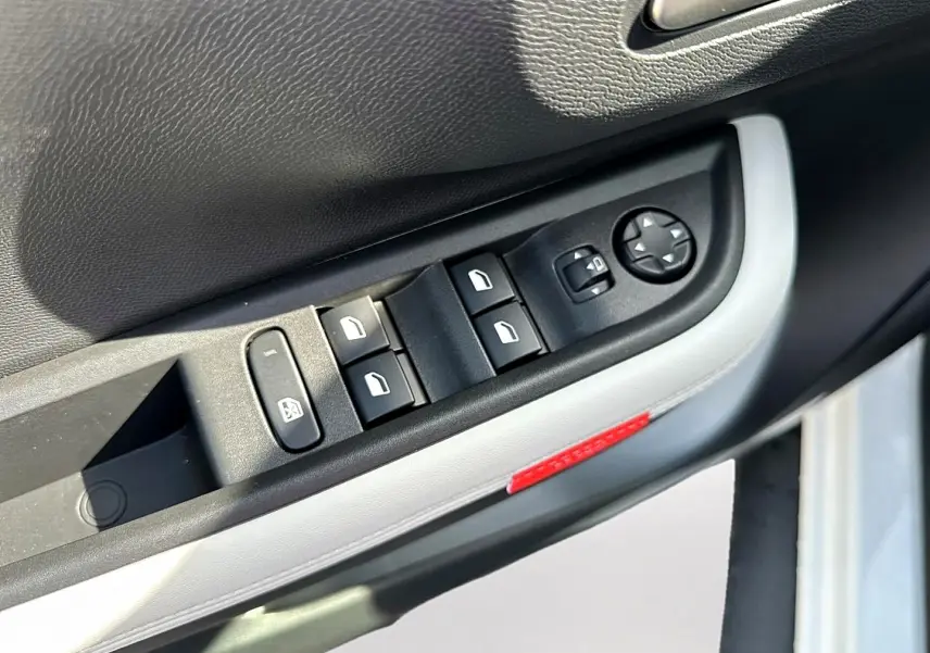 Gros plan sur la commande des vitres électriques côté conducteur de la Citroën C3 Aircross blanche, avec bouton de réglage des rétroviseurs.