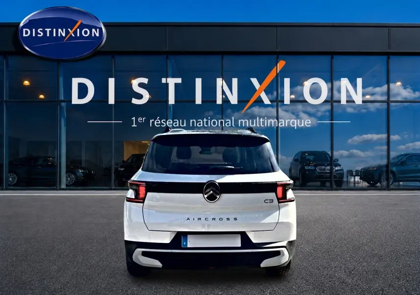 Vue arrière d'un Citroën C3 Aircross blanc 2026 devant une vitrine avec logo Distinxion.