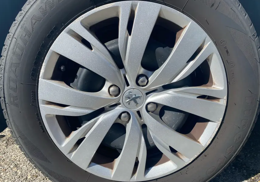 Gros plan sur la jante argentée d'une Peugeot 208 blanche, modèle 1.0 PureTech Active 2014, avec pneu Firestone.