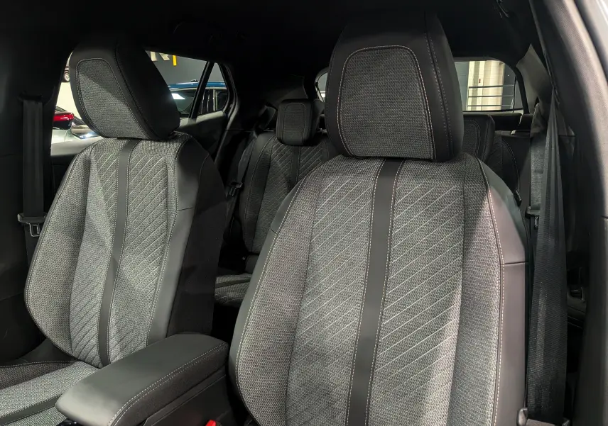 Gros plan sur les sièges avant en tissu gris et cuir noir du Peugeot 2008 Hybrid 145 e-DCS6 Allure 2025.