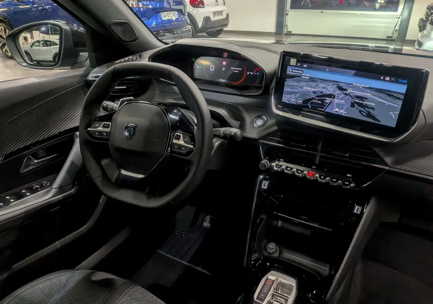 Intérieur du Peugeot 2008 Hybrid 145 Allure 2025, vue du poste de conduite avec écran tactile et volant compact noir.