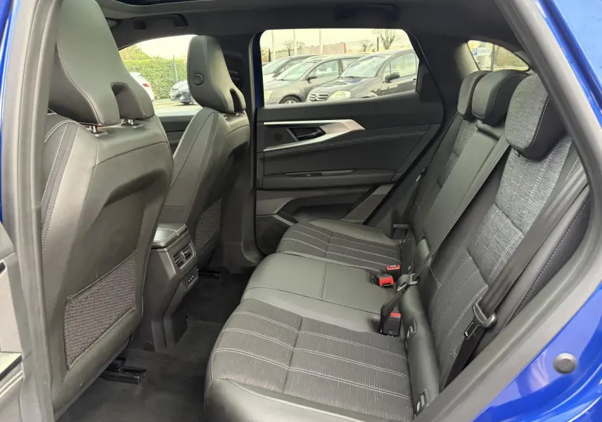 Vue intérieure arrière côté gauche du Renault Austral bleu Iron, montrant la banquette mixte tissu et cuir gris et les dossiers des sièges avant.