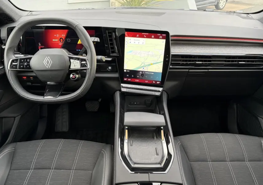 Vue intérieure avant du Renault Austral E-Tech 2025, tableau de bord noir avec écran tactile vertical et volant multifonction.