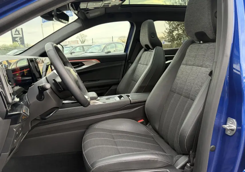 Vue intérieure côté conducteur du Renault Austral E-Tech bleu Iron, avec sièges gris tissu et toit panoramique visible.