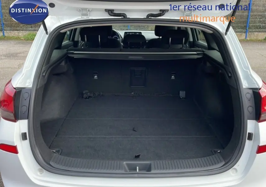 Vue arrière du coffre ouvert d'une Hyundai i30 SW blanche, montrant un espace de chargement vide et spacieux.