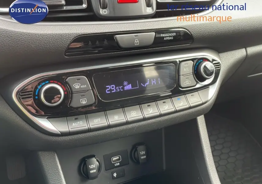 Vue rapprochée du tableau de bord de la Hyundai i30 SW blanc Atlas, montrant la console de climatisation digitale et les prises USB et 12V.