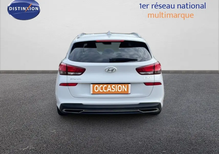 Vue arrière d'une Hyundai i30 SW blanche Atlas de 2022 avec feux arrière rouges et plaque "OCCASION" visible.