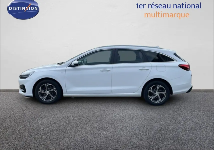 Profil droit d'une Hyundai i30 SW 2022 blanc atlas, break compact avec jantes alliage et vitres teintées.