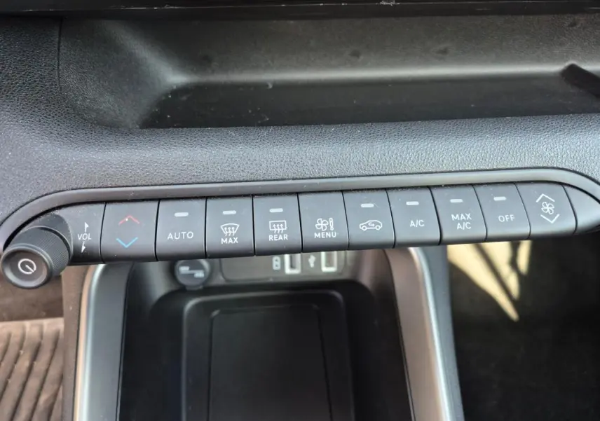 Gros plan sur la rangée de boutons de commande de la climatisation et volume dans l’habitacle noir du Jeep Avenger 2024.