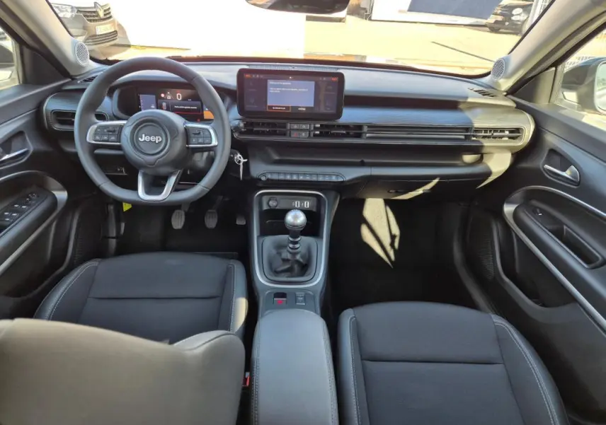 Vue intérieure avant du Jeep Avenger noir 2024, tableau de bord moderne avec écran tactile et boîte manuelle.