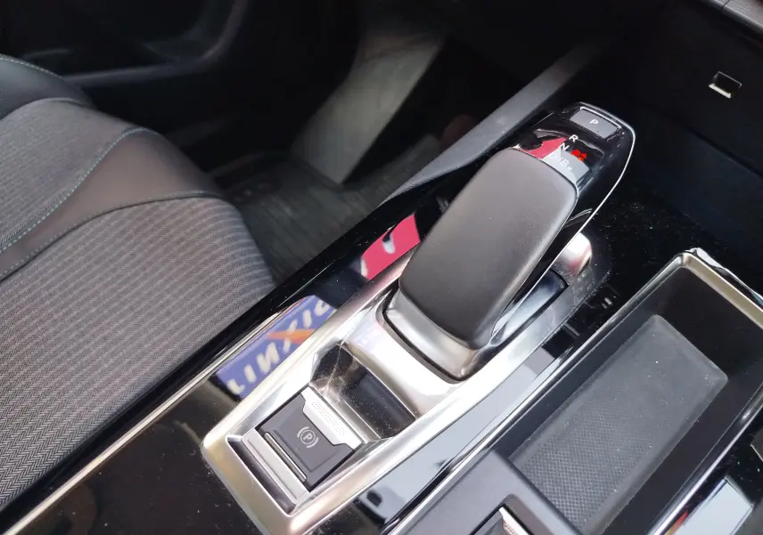 Gros plan sur la console centrale du Peugeot 3008 Hybrid 225ch, avec levier de vitesse automatique et frein électrique.