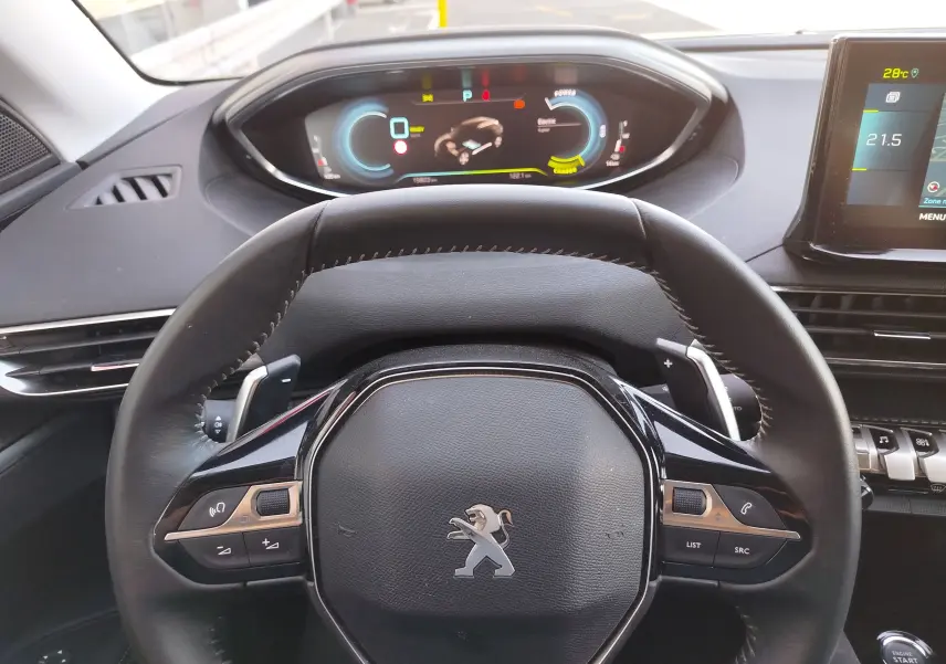 Vue intérieure centrée sur le volant noir du Peugeot 3008 Hybrid 225ch, avec tableau de bord numérique et écran tactile visibles.