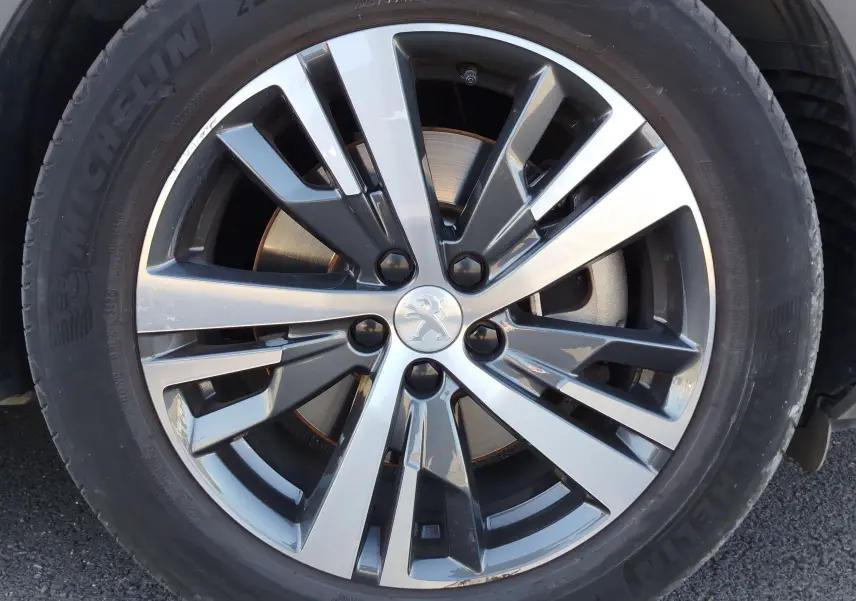 Gros plan sur la jante alliage bicolore du Peugeot 3008 Hybrid 225ch, avec logo lion au centre et pneu Michelin.