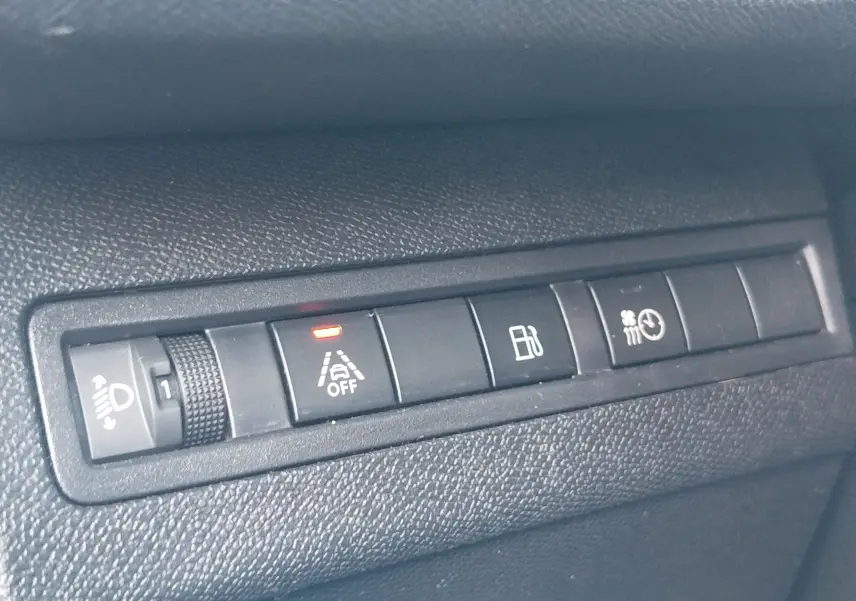 Gros plan sur les boutons de commande noirs du tableau de bord du Peugeot 3008 Hybrid 225ch, avec témoin orange allumé.