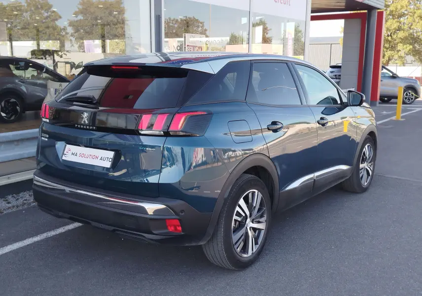 Vue 3/4 arrière droite d’un Peugeot 3008 Hybrid bleu Célèbes avec feux arrière à griffes et toit noir brillant.