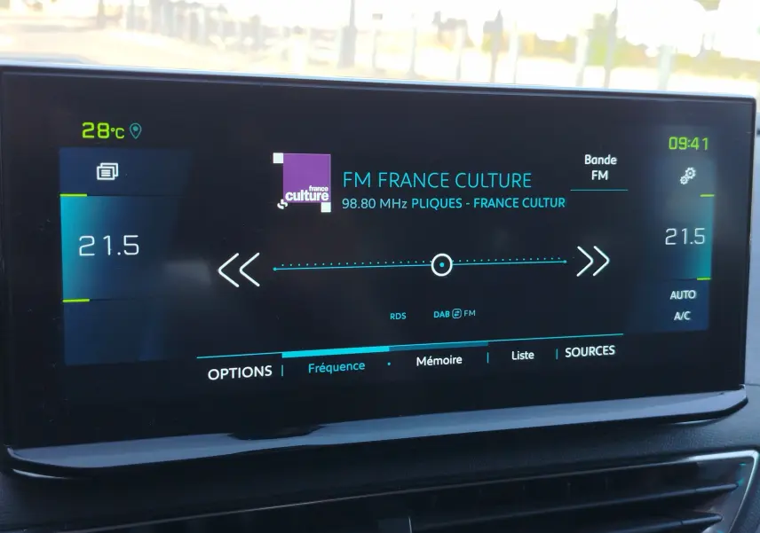 Écran tactile central du Peugeot 3008 Hybrid 225ch montrant la radio FM et la température intérieure à 21,5°C.
