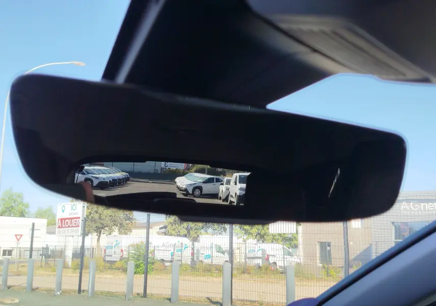 Vue du rétroviseur intérieur d’un Peugeot 3008 bleu Célèbes, reflétant des voitures blanches en stationnement à l’arrière.