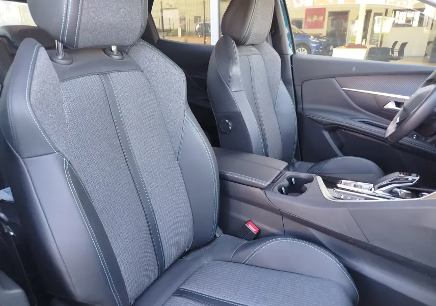 Vue intérieure côté droit du Peugeot 3008 Hybrid 225ch Allure 2022, sièges en tissu gris et cuir noir avec surpiqûres bleues.