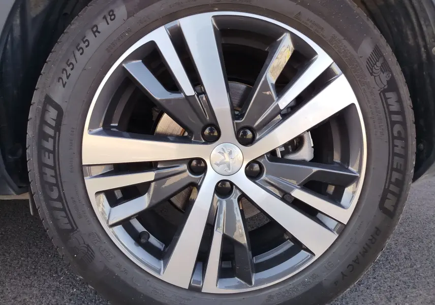 Gros plan sur la jante alliage bicolore et pneu Michelin d'un Peugeot 3008 Hybrid 225ch Allure 2022 bleu Célèbes.