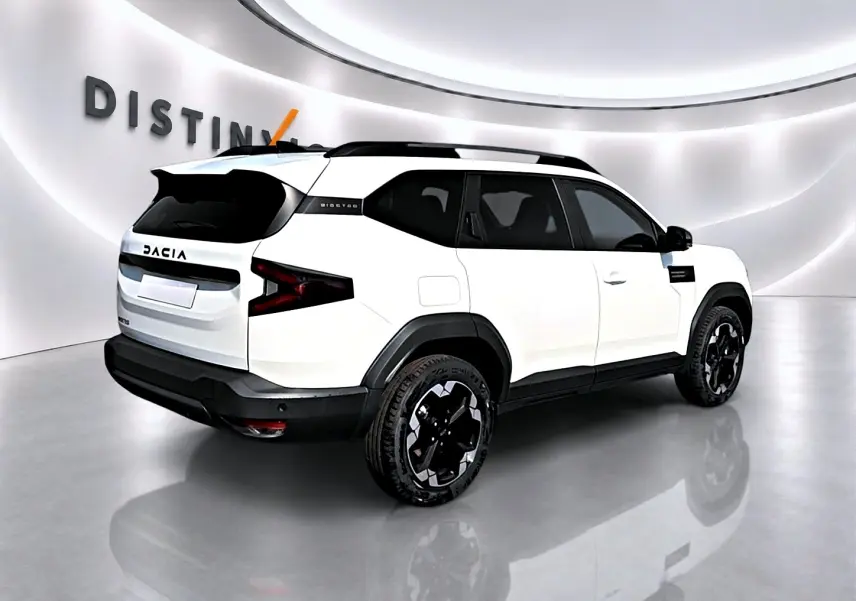Vue 3/4 arrière droite du Dacia Bigster blanc avec jantes noires et toit noir dans un showroom lumineux.