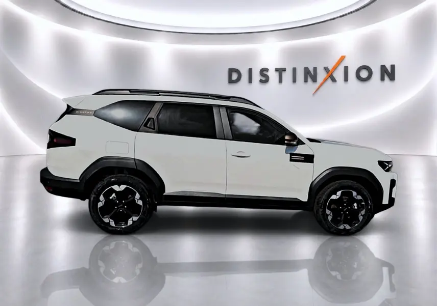 Profil gauche du SUV Dacia Bigster blanc 2026 avec jantes noires et barres de toit visibles en studio lumineux.