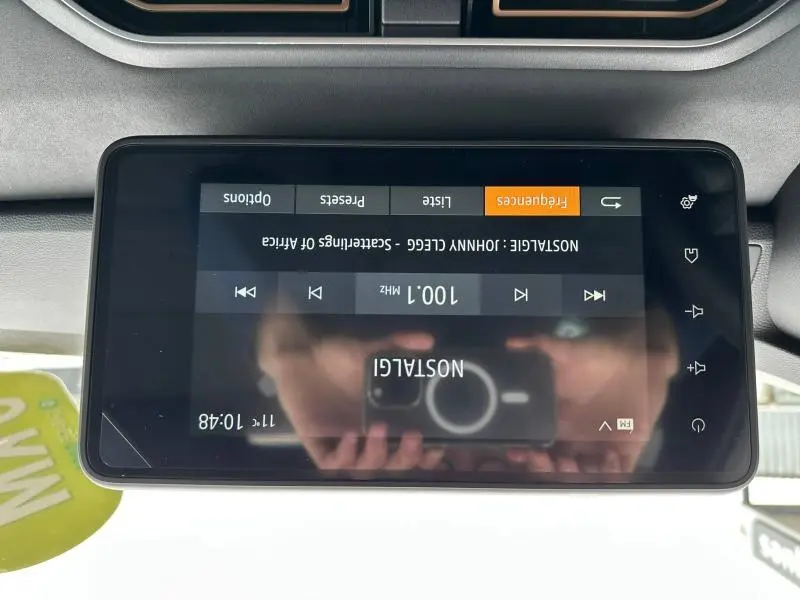 Écran tactile central du tableau de bord du Dacia Jogger affichant une radio FM, vue de dessus.