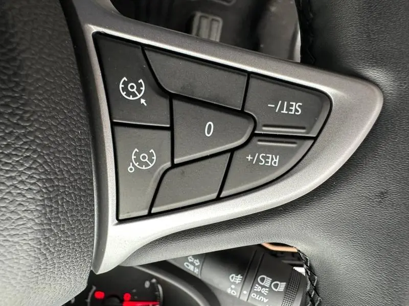 Gros plan sur les commandes de régulateur de vitesse au volant noir du Dacia Jogger brun Terracota métallisé 2024.