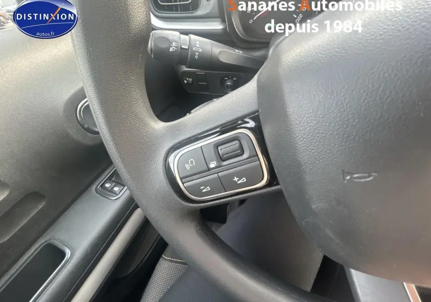 Gros plan sur les commandes audio au volant d'une Citroën C3 2023, intérieur gris foncé.
