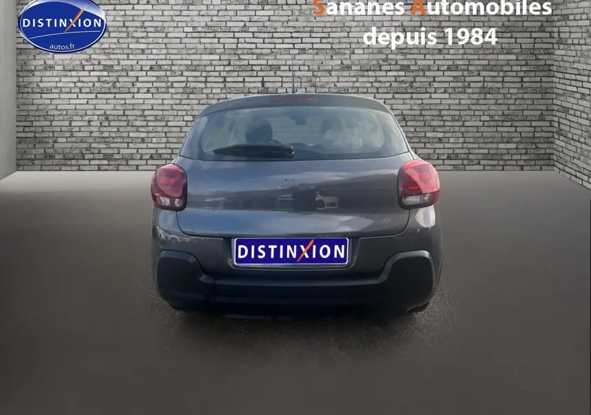 Vue arrière d'une Citroën C3 gris foncé 2023 avec feux rouges et pare-chocs noir mat sur sol gris.