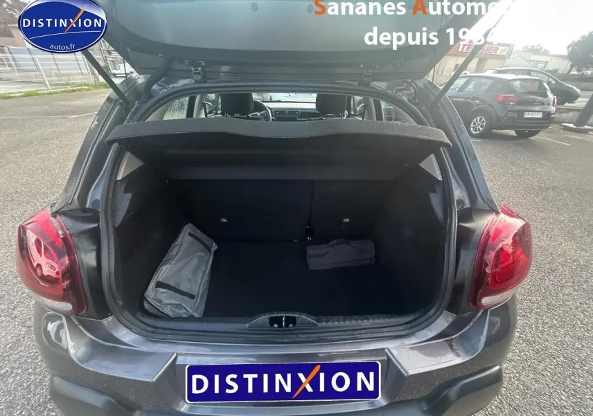 Coffre ouvert d'une Citroën C3 gris foncé vue arrière, avec intérieur de coffre vide et deux sacs posés.