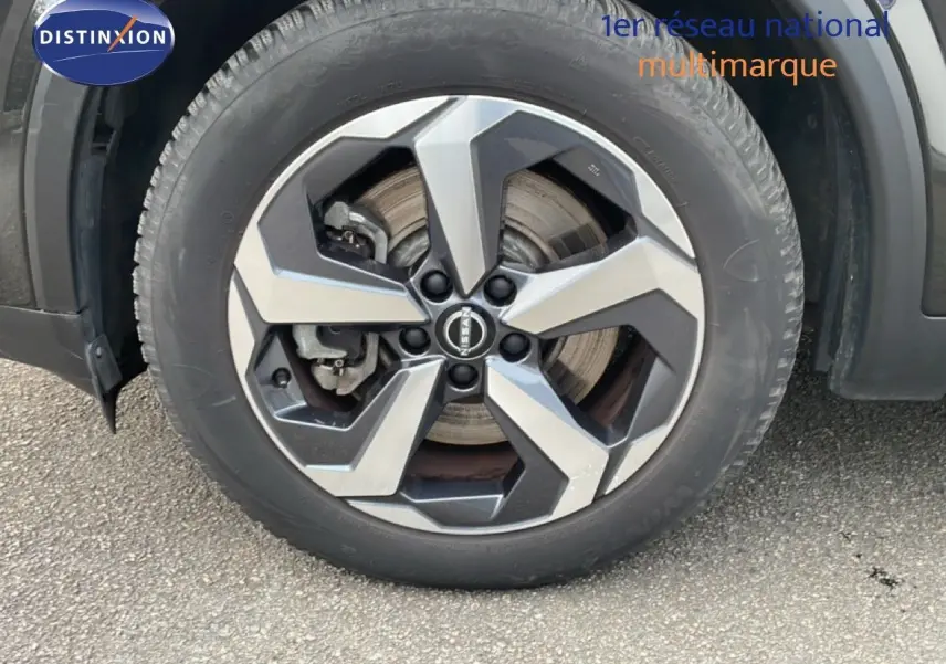 Gros plan sur la roue avant gauche du Nissan Qashqai noir métal 2023 avec jante alliage bicolore distinctive.